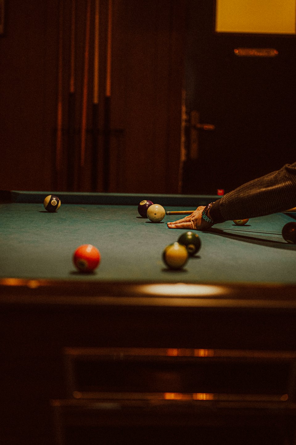 Hand holding a cue stick over a billiard table.