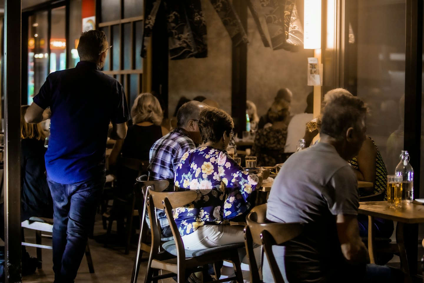 Diners and bar patrons socializing at wooden tables at night.