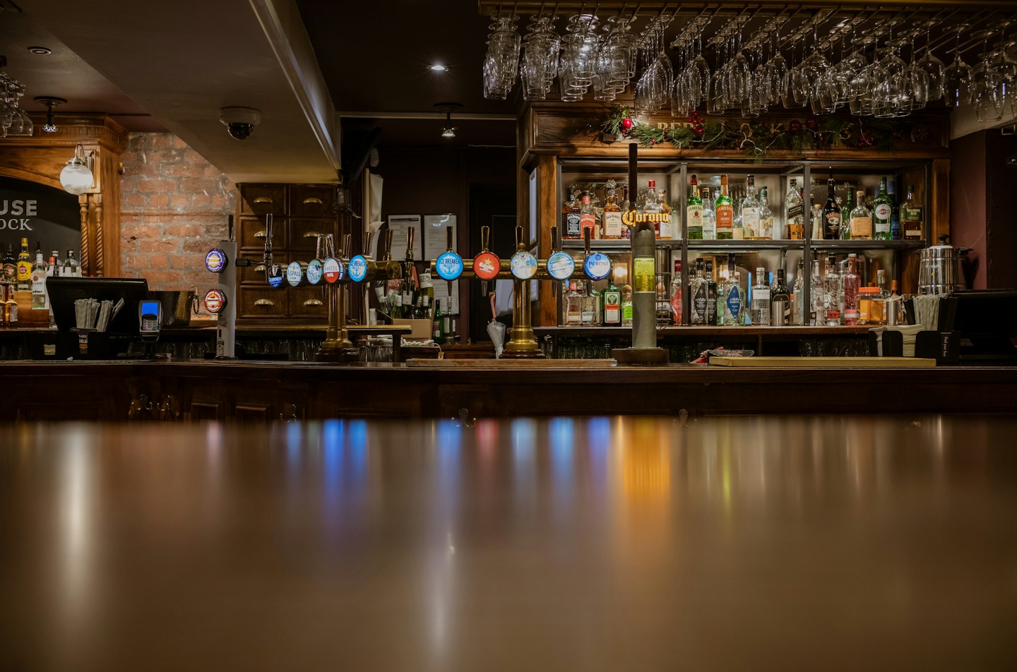 Beer taps stand on a polished wooden bar counter.