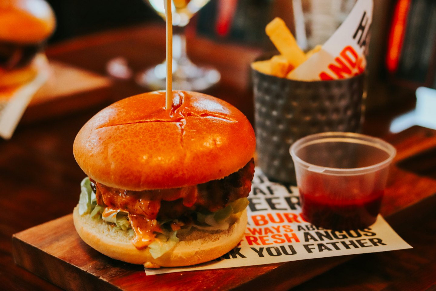 Gourmet burger with fries on a wooden table.