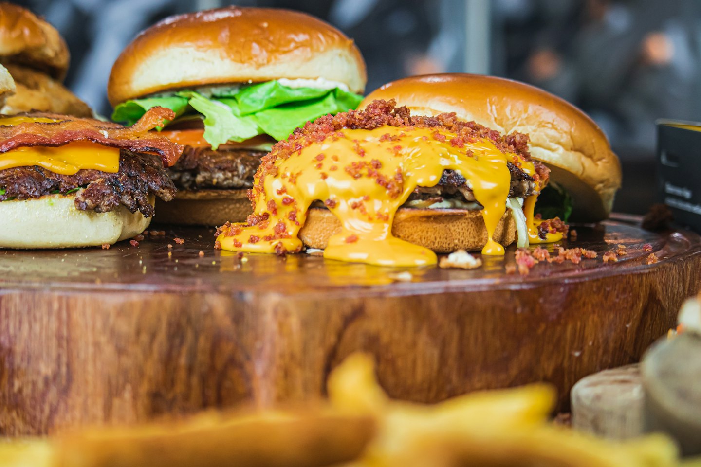 Three gourmet burgers rest on a rustic wooden board.