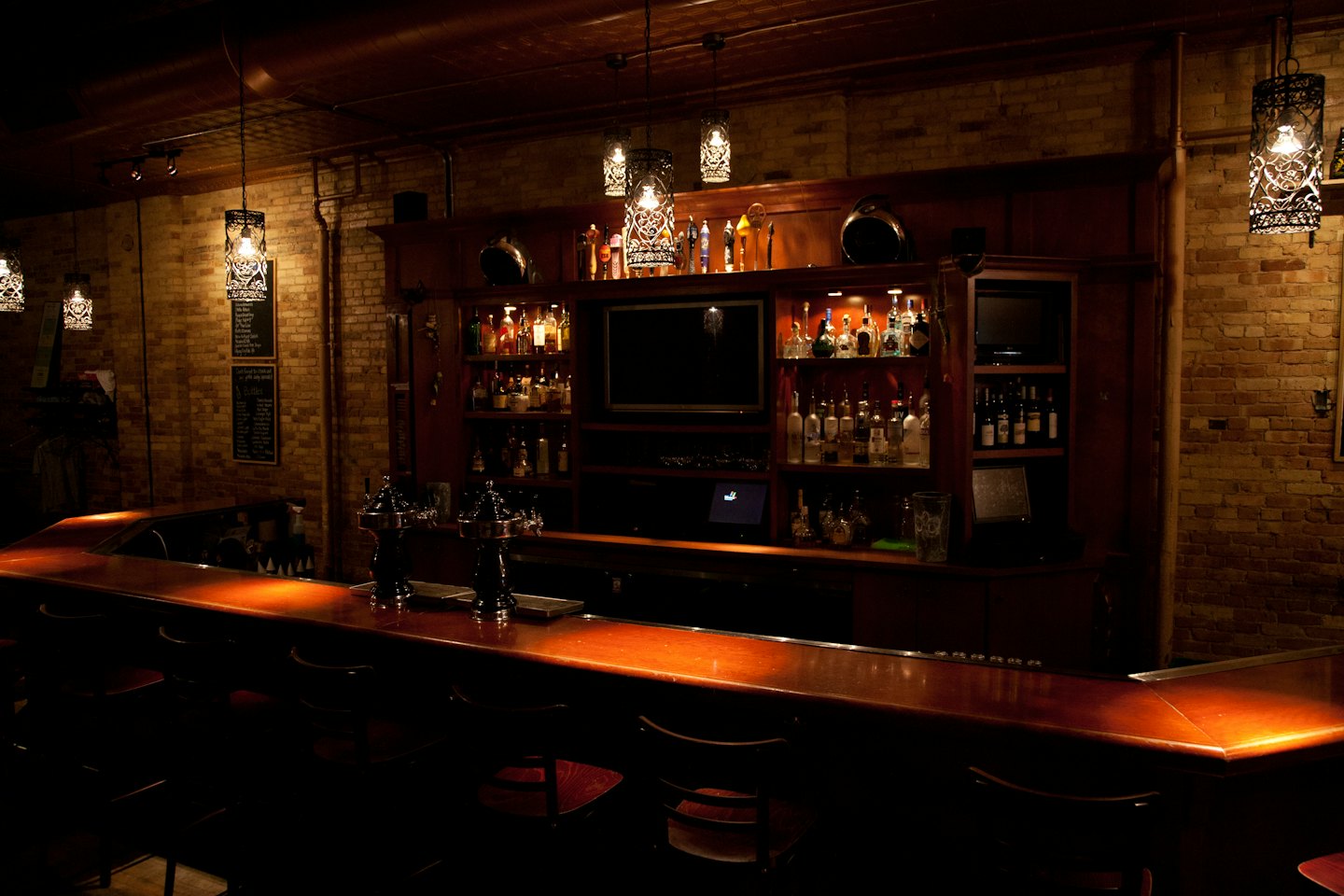 Wooden bar counter with beer taps and liquor bottles.