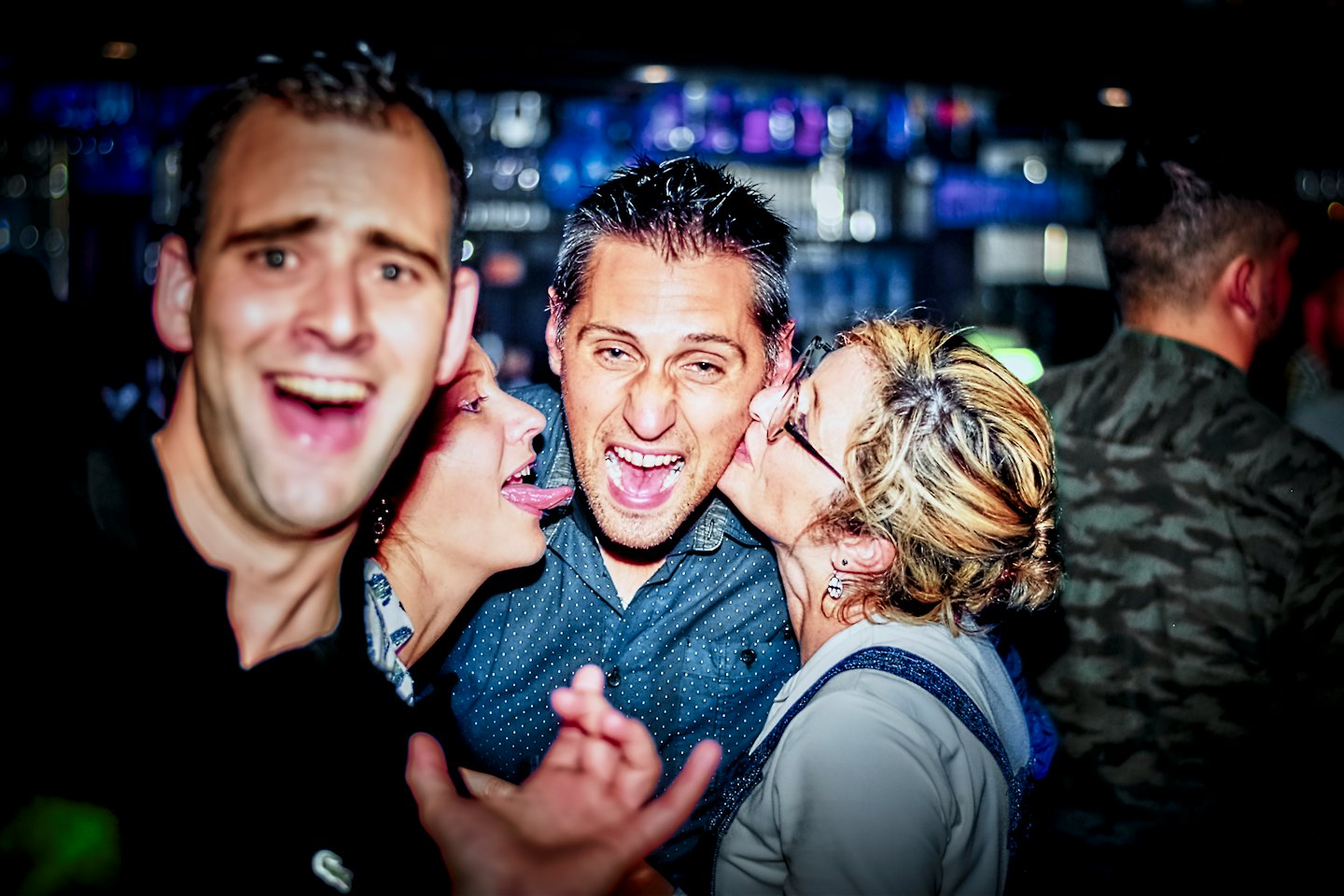 Friends laughing and interacting inside a crowded nightclub.