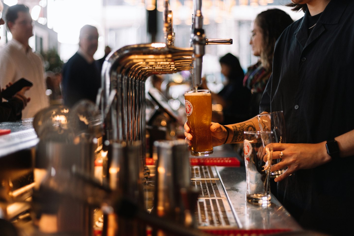Bartender pours golden beer from a tap into a glass.